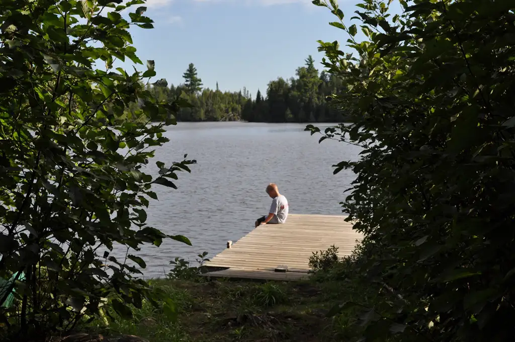 boy sitting on dock near poplar lake